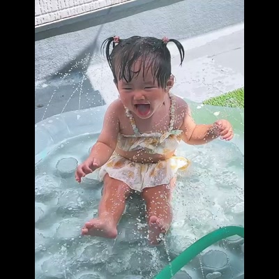 プールで水遊びする子どもと向き合う母親
