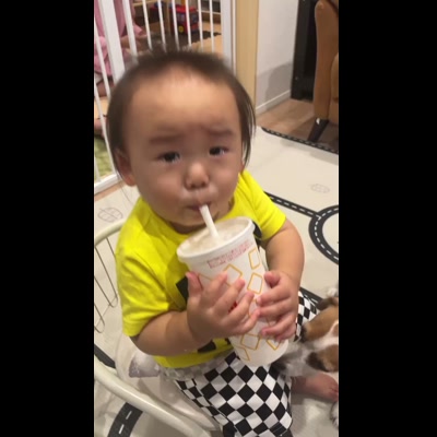 子どもがストローを上手く吸えず、照れ笑いしながら飲み直す